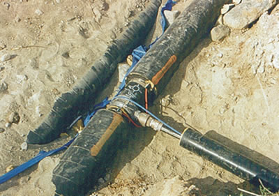 A typical 50 mm (2 in) service connection to a school at the Bearskin Lake Nation in northern Ontario.  Note the blue THERMOCABLE® on the service and red on the main.  Most THERMOCABLE® are color coded to identify watt density and operating voltage, small diameter service pipes requiring less wattage than mains.  A saddle / corporation stop insulation kit will be fitted to complete the installation.